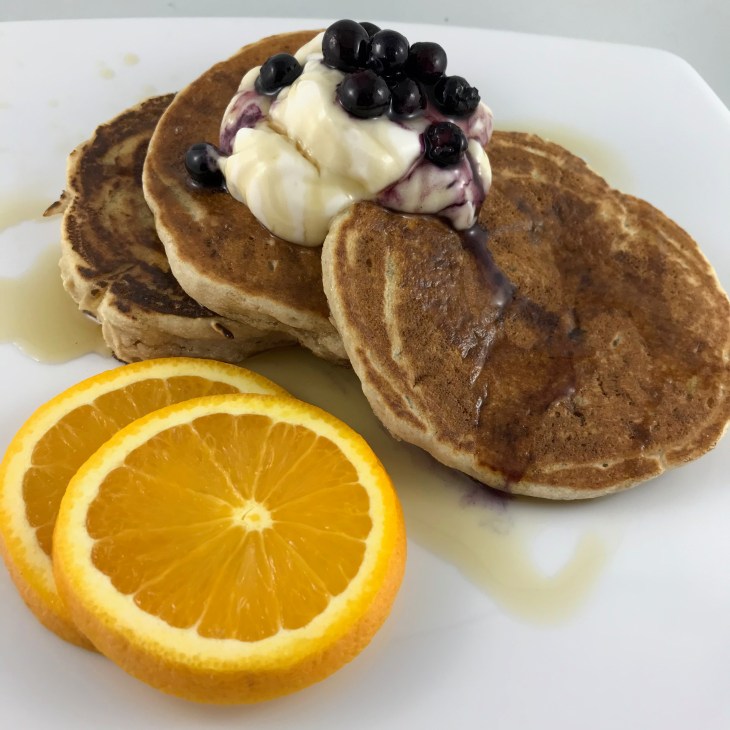 Pancakes, coconut yogurt, blueberries, maple syrup and orange slices